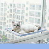 White cat resting on a blue hanging cat window hammock attached with suction cups on a window.